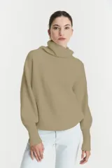 Sweater de punto acanalado en color beige, con cuello alto tipo tortuga, mangas largas con puños ajustados y diseño holgado.