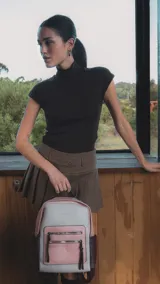 Mochila combinada en tonos beige, rosa y bordó, con apertura superior y dos bolsillos frontales con cierre metálico. Incluye bolsillos laterales y tres bolsillos internos. Tiene correa larga regulable y correas de espalda regulables.