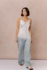 Musculosa de satén color crema con breteles finos regulables, escote en V y detalles de encaje en el escote, en diagonal sobre el delantero y en el ruedo.