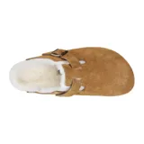 Zueco tipo mule de gamuza color tostado, con interior forrado en piel sintética blanca. Presenta una tira ajustable con hebilla metálica en el empeine y suela de goma con textura.