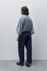 Pantalón jean de tiro alto con calce straight y pierna recta, confeccionado en denim de aspecto limpio. Cuenta con cinco bolsillos, cierre frontal con botón y presillas para cinturón.