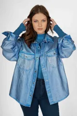 Sobrecamisa de jean color celeste con efecto metalizado, de corte holgado, con cuello camisero, botones frontales y dos bolsillos con solapa en el pecho.
