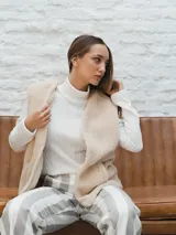 Chaleco color crema con textura de piel sintética, sin mangas y con forro interno.