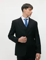 Traje de tres piezas color negro, compuesto por saco de dos botones, chaleco entallado y pantalón de corte slim, confeccionado en tejido de fantasía con spandex.