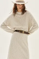 Sweater de tejido bouclé color crudo con cuello alto y sutil brillo por hilos de lurex. Posee mangas largas y un calce relajado.