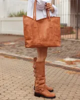 Bolso tipo shopper de cuero, color marrón tostado, con detalle de costura artesanal en el borde superior y correas largas para llevar al hombro.