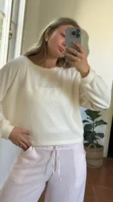 Blusa de lurex color blanco, de tejido suave, con escote redondo y puños en las mangas.