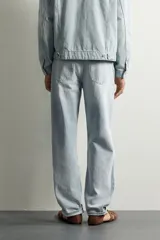 Jeans de corte recto color celeste claro, con tiro medio, diseño de cinco bolsillos, efecto lavado y bajo con acabado irregular deshilachado.