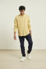 Camisa de manga larga confeccionada en una mezcla de algodón y lino, con cuello abotonado, cierre frontal de botones y un bolsillo en el pecho.