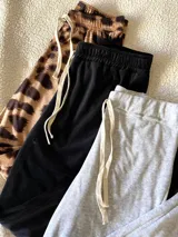 Pantalones de jogging de plush, uno con estampado animal print, otro negro y otro gris. Todos con cintura elastizada y cordón ajustable.