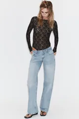 Jeans de tiro bajo con diseño wide leg y corte full length. Presenta cinco bolsillos, cierre frontal con cremallera y botón metálico, en un lavado de denim claro.