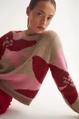 Sweater de jacquard con diseño floral abstracto, cuello redondo y mangas largas. Presenta una combinación de colores en tonos bordó, rosa y beige, con texturas diferenciadas en el tejido.