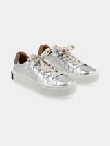 Sneaker de plataforma color plata con textura efecto cocodrilo, detalle de gamuza marrón en el talón y suela blanca con inscripción en el lateral.
