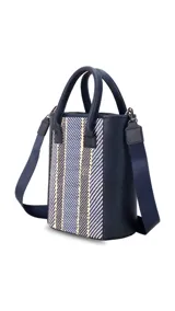 Matera azul marino con diseño frontal en telar rayado en tonos azules, blancos y amarillos. Cuenta con doble asa de mano y correa de hombro ajustable.