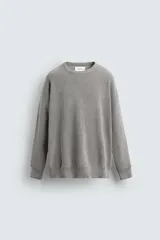 Jersey de punto con textura acanalada, cuello redondo y manga larga. Presenta un corte regular fit con acabados en rib en puños y bajo.