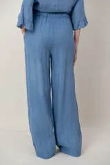 Pantalon de lino color azul, de corte ancho y relajado, con cintura elastizada ajustable mediante cordón y bolsillos laterales. Presenta detalles de alforzas en los bajos.