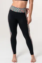 Calza deportiva de tiro alto con cintura elástica reforzada. Presenta un diseño bicolor que combina paneles laterales y faja con estampado animal print en tonos coral y turquesa sobre una base negra.