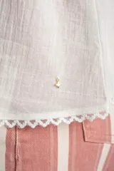 Top blanco de algodón peinado con tirantes finos, escote en V con detalle de encaje y cierre frontal abotonado. Presenta inserciones de encaje transparente en el abdomen y un diseño fluido en la parte inferior.