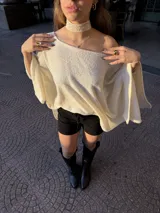 Poncho de hilo liviano en color crema, con diseño de cuello redondo y caída fluida, ideal para media estación.
