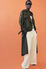 Trench oversize de Zara Woman Collection, color verde militar, con cuello solapa, cierre frontal cruzado con botones y cinturón ajustable del mismo tejido. Presenta mangas largas con trabillas ajustables y bolsillos delanteros.