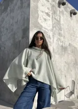 Poncho de hilo liviano en color verde claro, con diseño de cuello alto y caída fluida. Prenda versátil ideal para media estación.