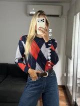 Sweater de tejido de punto con diseño de rombos en tonos verde oliva, verde oscuro y blanco. Presenta cuello redondo, mangas largas con puños acanalados y un corte holgado.