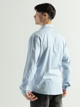 Camisa de manga larga color gris oscuro, confeccionada en algodón, con cuello clásico, cierre frontal con botones, bolsillo de parche en el pecho y corte clásico.