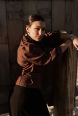 Camisa blanca con lunares celestes, de corte clásico, con cuello camisero y mangas largas abullonadas.