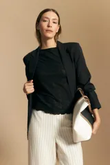 Top sin mangas de jacquard color negro, con cuello cerrado y silueta recta. Presenta una textura trabajada con relieve y una terminación suavemente ondulada en el ruedo.