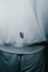 Campera de jogging celeste con cierre frontal, capucha con detalle en relieve, bolsillos tipo canguro y estampado central con efecto spray.