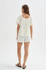 Blusa holgada de lyocell color blanco, con diseño plisado, escote cuadrado y mangas cortas abullonadas.