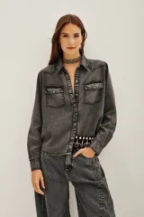 Camisa de estilo tejano en color negro lavado, con cuello camisero, cierre frontal con botones metálicos y dos bolsillos delanteros con solapa.