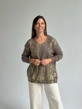 Sweater de punto color verde seco con estampado de salpicaduras en color dorado, cuello en V y mangas largas.