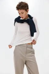 Pantalón sastrero de sarga color beige, con cintura clásica, trabillas para cinto y cierre frontal oculto. Presenta bolsillos laterales al bies, pliegues frontales y piernas rectas con raya marcada.