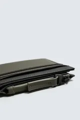 Cartera de acabado engomado en color verde militar y negro. Cuenta con un compartimento principal para billetes, seis ranuras internas para tarjetas y dos externas. Incluye un monedero con cierre de cremallera en uno de los laterales.