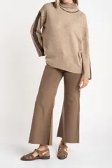 Polera oversize color beige melange, de punto con mangas largas y detalles de franjas marrones en las mangas y cuello.