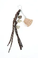 Llavero decorativo con mosquetón metálico, compuesto por tiras de cordón marrón con costuras blancas, tiras con estampado animal print tipo leopardo, colgantes en forma de corazón con motivos estampados y un dije en miniatura de gorro tejido de lana en color tostado con pompón blanco.