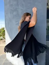 Ruana negra tejida en lana con aplique de cuero en la espalda y flecos en el ruedo.