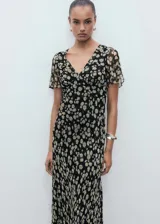 Vestido midi de gasa con estampado floral, cuello en pico y mangas cortas. Presenta un diseño recto, cierre de cremallera lateral y forro interior.