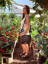 Cartera bandolera negra de cuero con forro interno de tela, detalle de flecos de cuero marrón en la parte inferior y asa larga regulable.