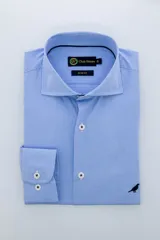 Camisa de vestir de corte slim-fit, color azul con microestampado a cuadros. Presenta cuello clásico, cierre frontal con botones y puños con doble botón. Incluye un pequeño bordado de un ave en la parte inferior frontal.