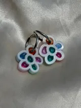 Par de aros colgantes con forma de flor, con pétalos de acrílico de colores translúcidos (naranja, verde azulado, fucsia, lila y celeste) y argollas de metal plateado.