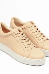 Zapatillas color beige claro, con capellada de cuero suave y acolchado, forro y plantilla de cuero vacuno, y suela de EVA. Tienen una plataforma de 3.8 cm en la parte trasera y 3.2 cm en la delantera.