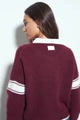 Campera de punto tipo cardigan en color bordó, con cierre frontal, cuello redondo y diseño estilo universitario. Presenta el número 54 bordado en blanco en el pecho y franjas blancas en las mangas.