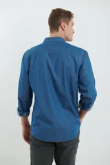 Camisa de jean azul oscuro de manga larga con cuello abotonado y bolsillo en el pecho.