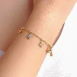Pulsera de cadena eslabonada dorada con dijes colgantes en forma de flor, decorados con pequeñas piedras brillantes.