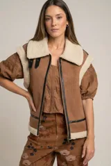 Chaleco estilo gamulán color marrón, con interior y cuello de corderito sintético en color crema. Presenta cierre frontal con detalles en cuero sintético negro y diseño oversize.
