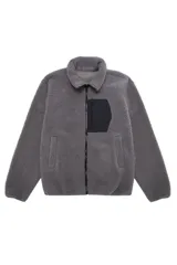 Campera de tejido polar tipo teddy en color gris, con cuello camisero, cierre frontal de cremallera y bolsillo funcional en el pecho con solapa de contraste.
