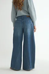 Jean de corte wide leg con diseño de costuras verticales decorativas en el frente, tiro medio y cierre frontal con botón y cremallera.