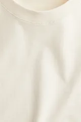 Remera color crema de corte recto en punto suave de algodón con cuello redondo ribeteado y hombros ligeramente caídos.